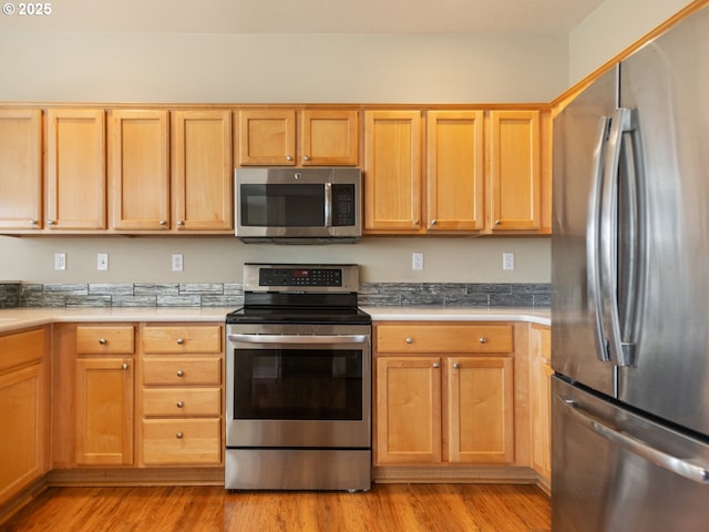 kitchen with light wood finished floors, stainless steel appliances, and light countertops