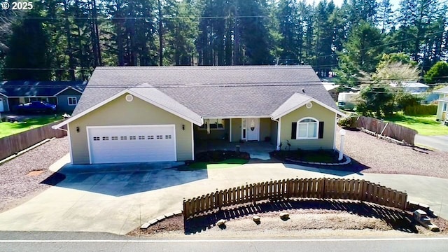 view of front facade with a fenced front yard, concrete driveway, a shingled roof, and an attached garage