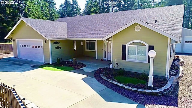 ranch-style home with roof with shingles, a garage, driveway, and fence