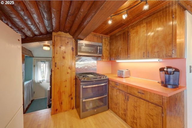 604 15th Ave, Seaside, OR 97138 - kitchen with appliances with stainless steel finishes, light wood-style floors, light countertops, brown cabinets, and a wood ceiling with exposed beams