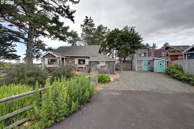 604 15th Ave, Seaside, OR 97138 - view of front of property featuring stone siding, driveway, roof with shingles, and a storage shed