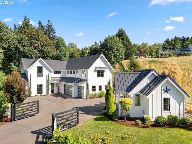 modern farmhouse featuring a standing seam roof, metal roof, aphalt driveway, and board and batten siding