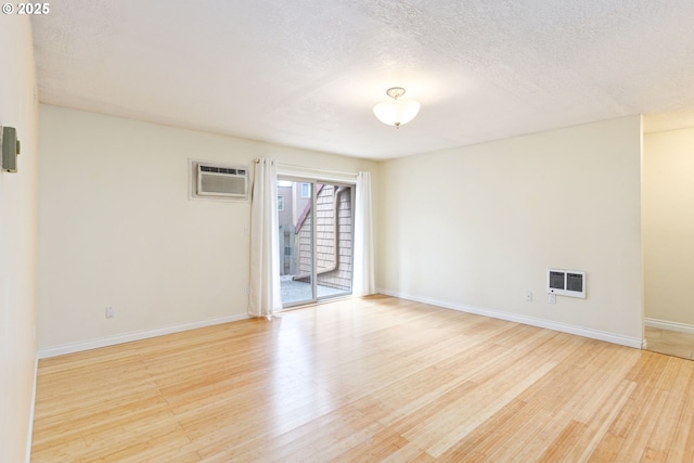 125 Oswego, Lake Oswego, OR 97035 - empty room featuring light wood-type flooring, baseboards, an AC wall unit, and a textured ceiling