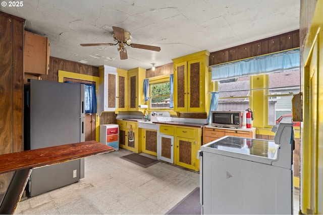 721 Columbia Blvd, Saint Helens, OR 97051 - kitchen with stainless steel appliances, light floors, wood walls, and ceiling fan