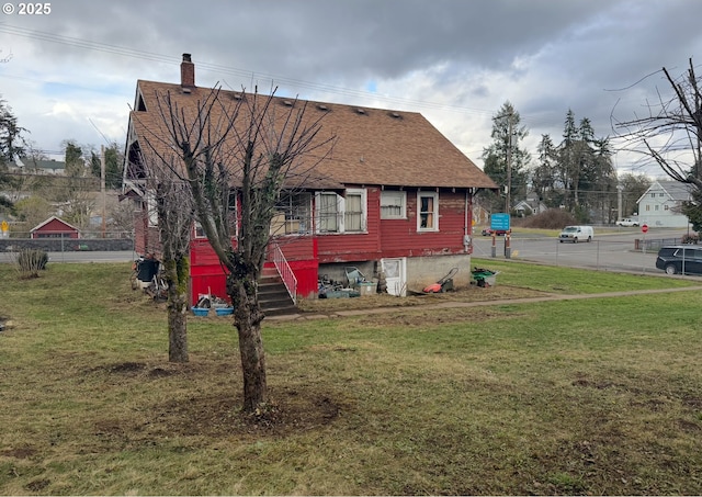 exterior space featuring a chimney, roof with shingles, and a front yard