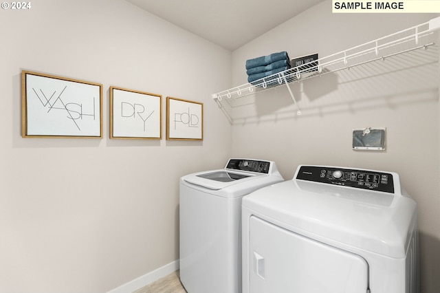 clothes washing area with washing machine and dryer and light hardwood / wood-style flooring