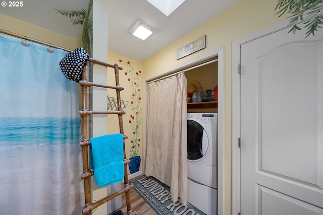clothes washing area featuring washer / clothes dryer, wood finished floors, and a skylight