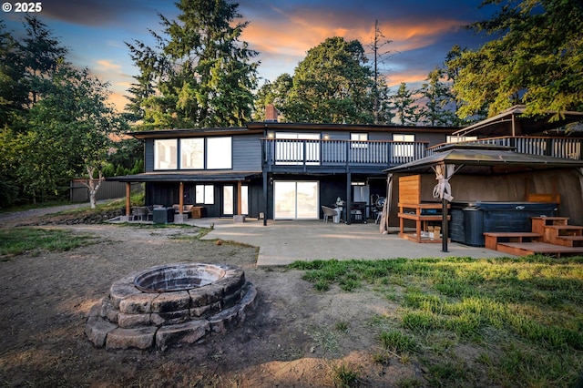 20700 SW Cherry Hill Rd, Sheridan, OR 97378 - back of house at dusk with a hot tub, a patio, and an outdoor living space with a fire pit