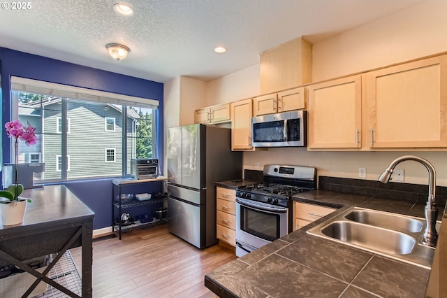390 NW 116th Ave Unit 103, Portland, OR 97229 - kitchen featuring appliances with stainless steel finishes, light brown cabinets, light wood-style floors, a textured ceiling, and recessed lighting