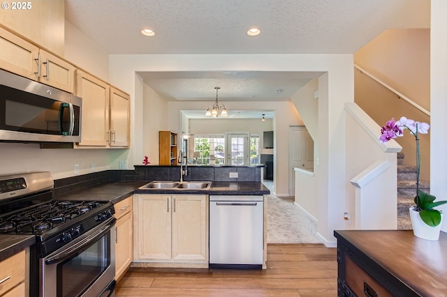 390 NW 116th Ave Unit 103, Portland, OR 97229 - kitchen featuring appliances with stainless steel finishes, light brown cabinetry, a peninsula, dark countertops, and a textured ceiling