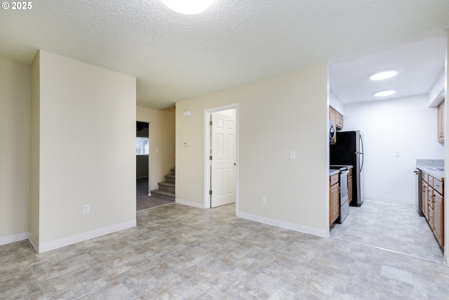 kitchen featuring brown cabinets, stainless steel appliances, light countertops, and baseboards
