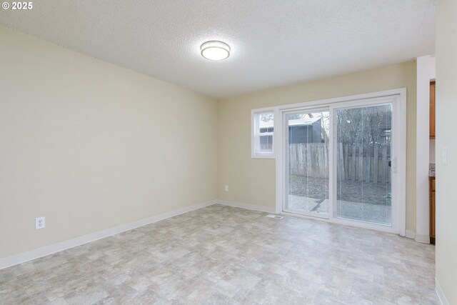 unfurnished room with baseboards and a textured ceiling