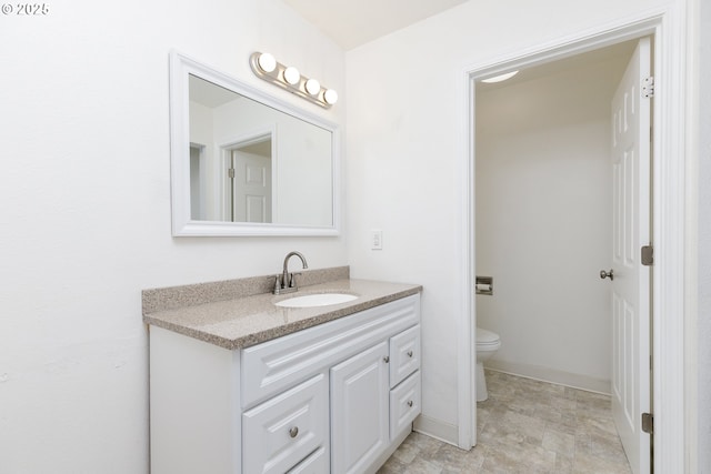 bathroom with toilet, vanity, and baseboards