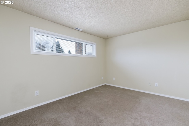 empty room featuring baseboards, visible vents, a textured ceiling, and carpet