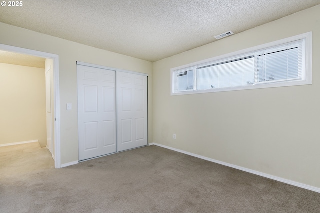 unfurnished bedroom with visible vents, baseboards, carpet floors, a closet, and a textured ceiling