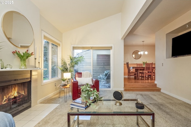 carpeted living room featuring a tile fireplace, vaulted ceiling, and an inviting chandelier