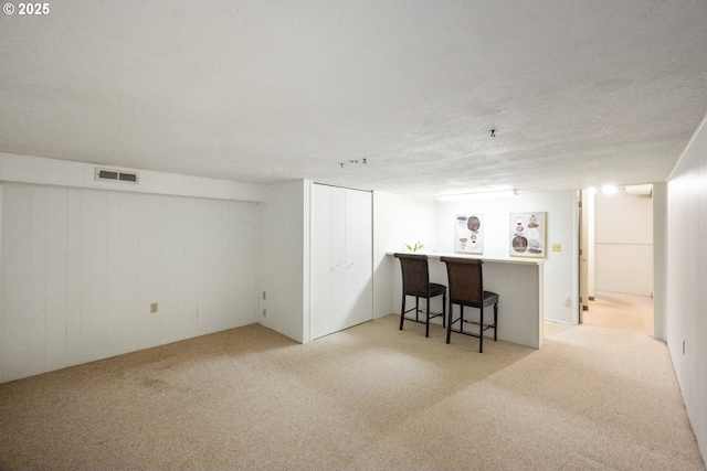 bar with light colored carpet and a textured ceiling