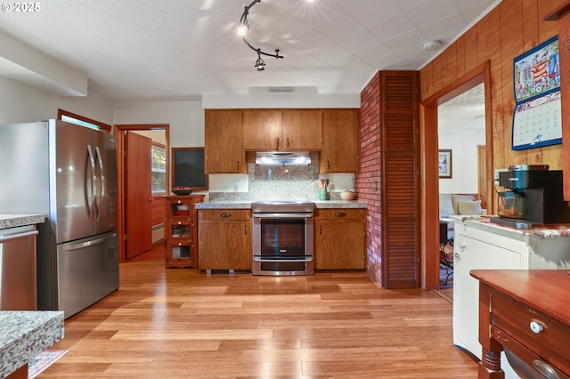 25701 S Morgan Rd, Estacada, OR 97023 - kitchen with appliances with stainless steel finishes, brown cabinetry, exhaust hood, light countertops, and light wood finished floors