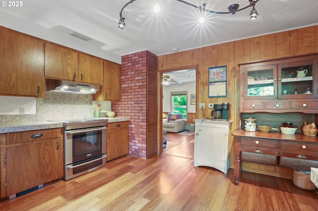 25701 S Morgan Rd, Estacada, OR 97023 - kitchen with under cabinet range hood, electric range, brown cabinetry, light wood-type flooring, and backsplash