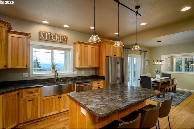 kitchen with stainless steel appliances, light wood-type flooring, a sink, and a kitchen breakfast bar