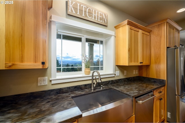 kitchen featuring appliances with stainless steel finishes, dark stone counters, and a sink