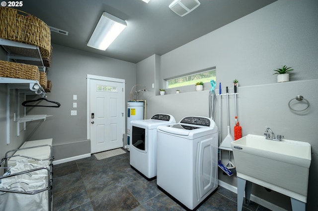 laundry area with laundry area, a sink, baseboards, water heater, and washer and dryer