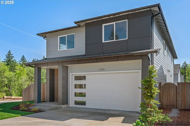 contemporary home with fence, an attached garage, and concrete driveway