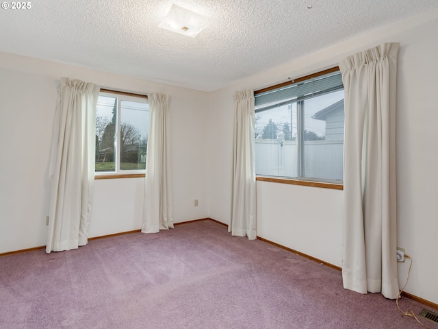 carpeted empty room with baseboards and a textured ceiling