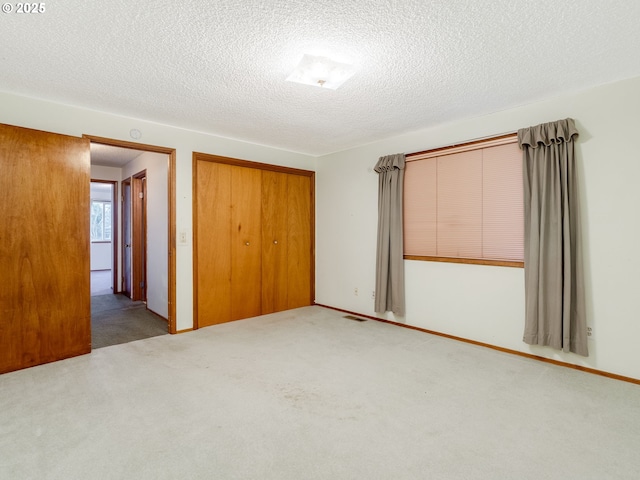 unfurnished bedroom with a textured ceiling, visible vents, a closet, and carpet flooring