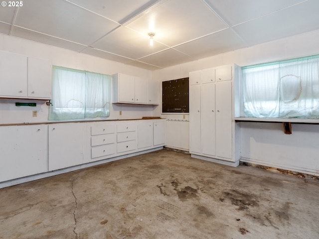 kitchen with concrete floors and white cabinetry