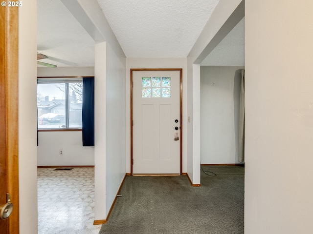 foyer with a textured ceiling, visible vents, and baseboards