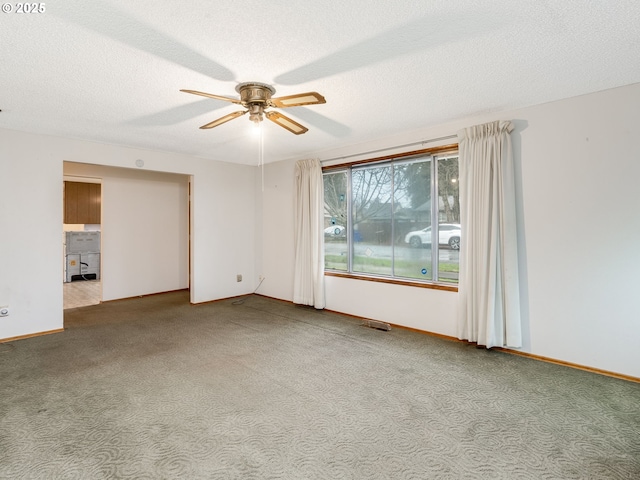 carpeted spare room with a textured ceiling, visible vents, a ceiling fan, and baseboards