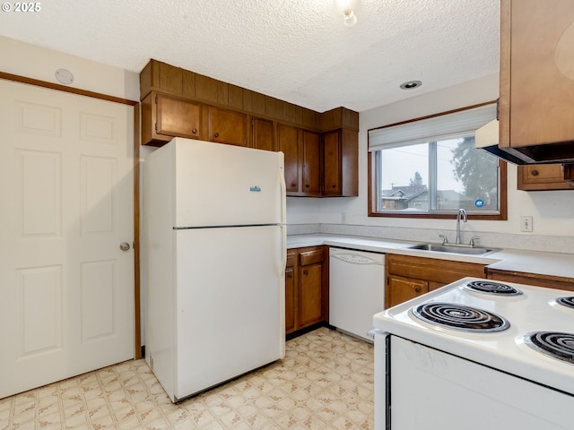 kitchen featuring light floors, white appliances, brown cabinetry, and a sink