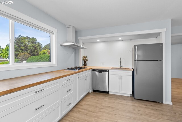 611 Summit Ridge Dr, The Dalles, OR 97058 - kitchen with stainless steel appliances, wood counters, wall chimney exhaust hood, a sink, and white cabinetry