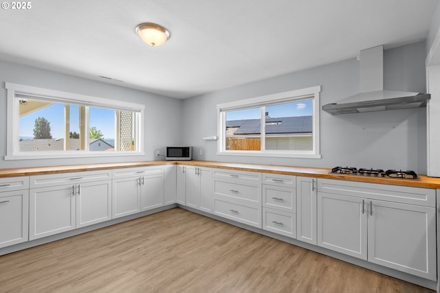 611 Summit Ridge Dr, The Dalles, OR 97058 - kitchen featuring wooden counters, wall chimney exhaust hood, stainless steel microwave, gas cooktop, and light wood finished floors