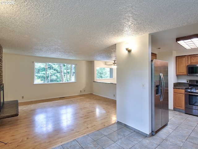 1745 NE W Devils Lake Rd, Lincoln City, OR 97367 - kitchen with appliances with stainless steel finishes, open floor plan, a textured ceiling, dark countertops, and brown cabinets