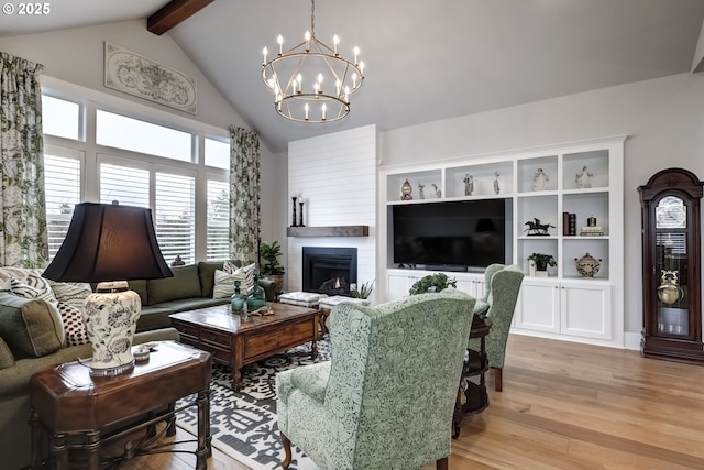 living room with vaulted ceiling with beams, a fireplace, a chandelier, and light hardwood / wood-style floors