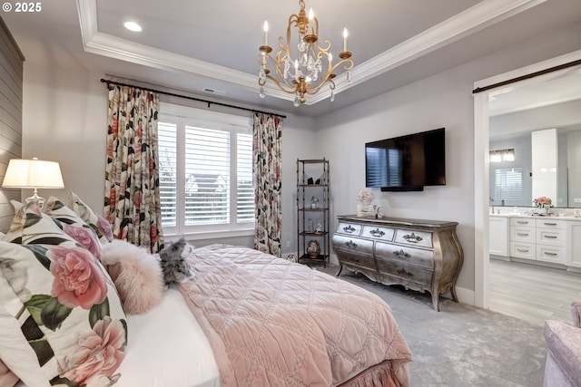 bedroom with crown molding, light colored carpet, a tray ceiling, and ensuite bath