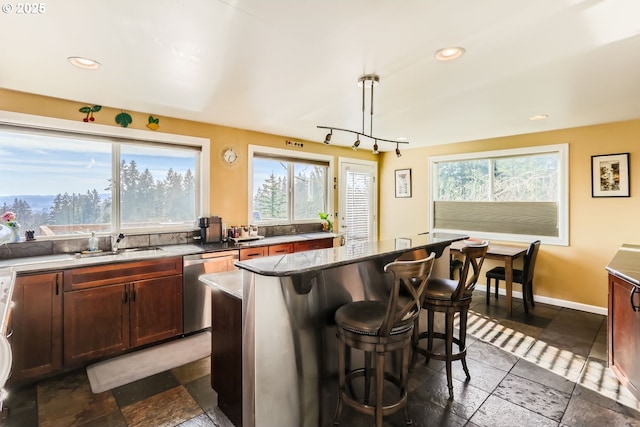 kitchen with dishwasher, sink, decorative light fixtures, a kitchen island, and a breakfast bar area