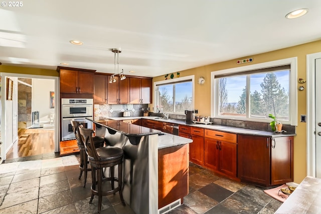 kitchen with hanging light fixtures, appliances with stainless steel finishes, backsplash, a kitchen island, and a breakfast bar area