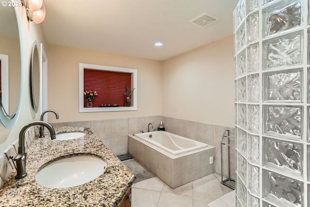 bathroom with tiled tub, tile patterned floors, and vanity