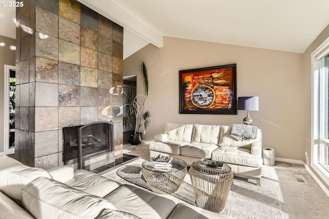 carpeted living room with a tiled fireplace and vaulted ceiling with beams