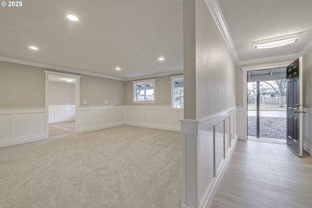 interior space with ornamental molding, light colored carpet, and a textured ceiling