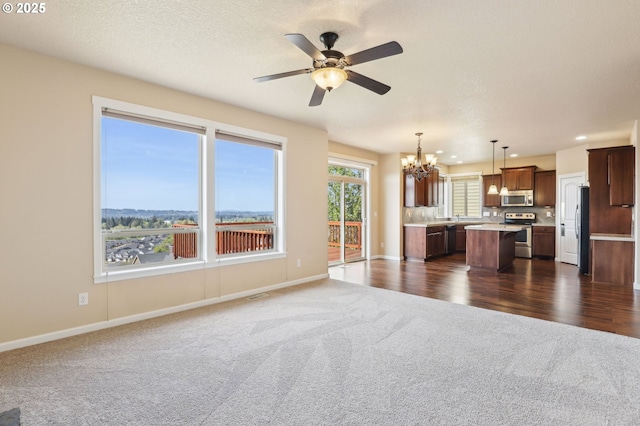 unfurnished living room featuring visible vents, dark carpet, baseboards, recessed lighting, and ceiling fan with notable chandelier