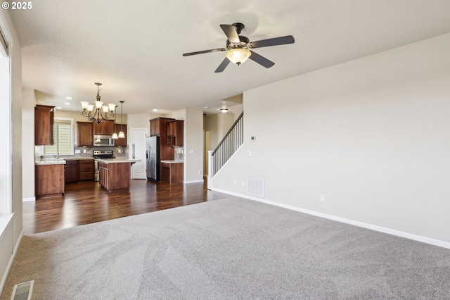 unfurnished living room featuring baseboards, visible vents, and dark carpet