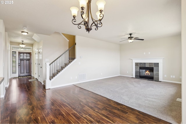 unfurnished living room with stairs, visible vents, wood finished floors, and ceiling fan with notable chandelier