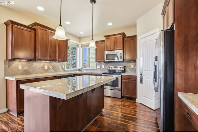 kitchen with a center island, light countertops, dark wood finished floors, appliances with stainless steel finishes, and decorative light fixtures
