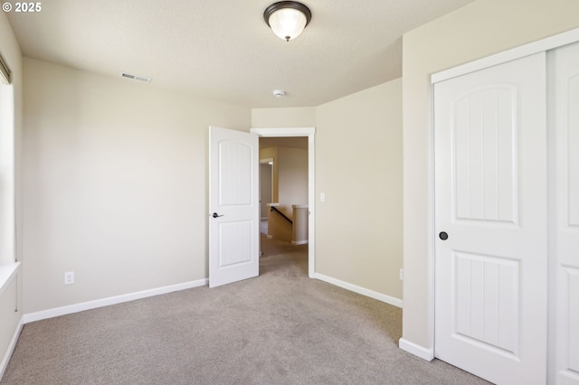 unfurnished bedroom featuring visible vents, carpet, baseboards, and a closet