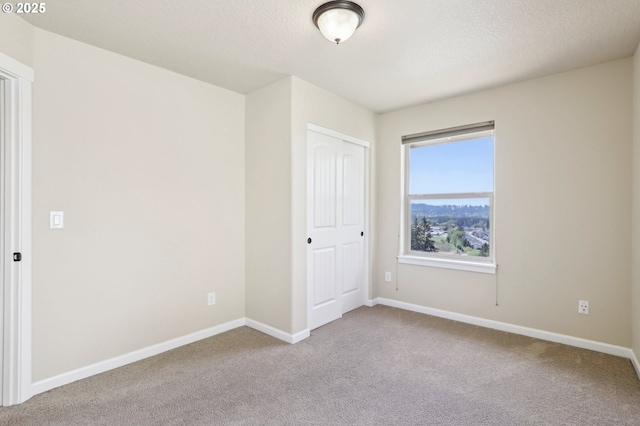 carpeted spare room with baseboards and a textured ceiling