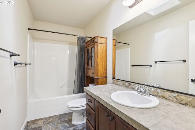 bathroom featuring vanity, toilet, shower / bathtub combination with curtain, stone finish floor, and baseboards